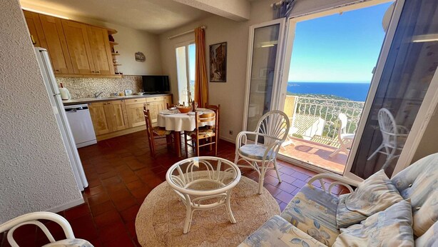 A balcony with a view of the sea, a dining area with a table and chairs, and a living area with a sofa and a patterned rug. - 2-room Apartment - Sea View - Pool - Cavalaire (Cavalaire-sur-Mer)