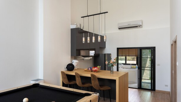 Una cocina moderna con mesa de billar, mesa de comedor de madera y sillas.