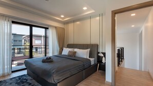 Un dormitorio moderno con una cama grande, vistas al exterior a través de una puerta corredera y una mesita de noche con un objeto decorativo.