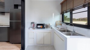 Una cocina moderna con horno empotrado, microondas y cafetera.