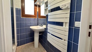 Een badkamer met een wastafel, spiegel en raam.