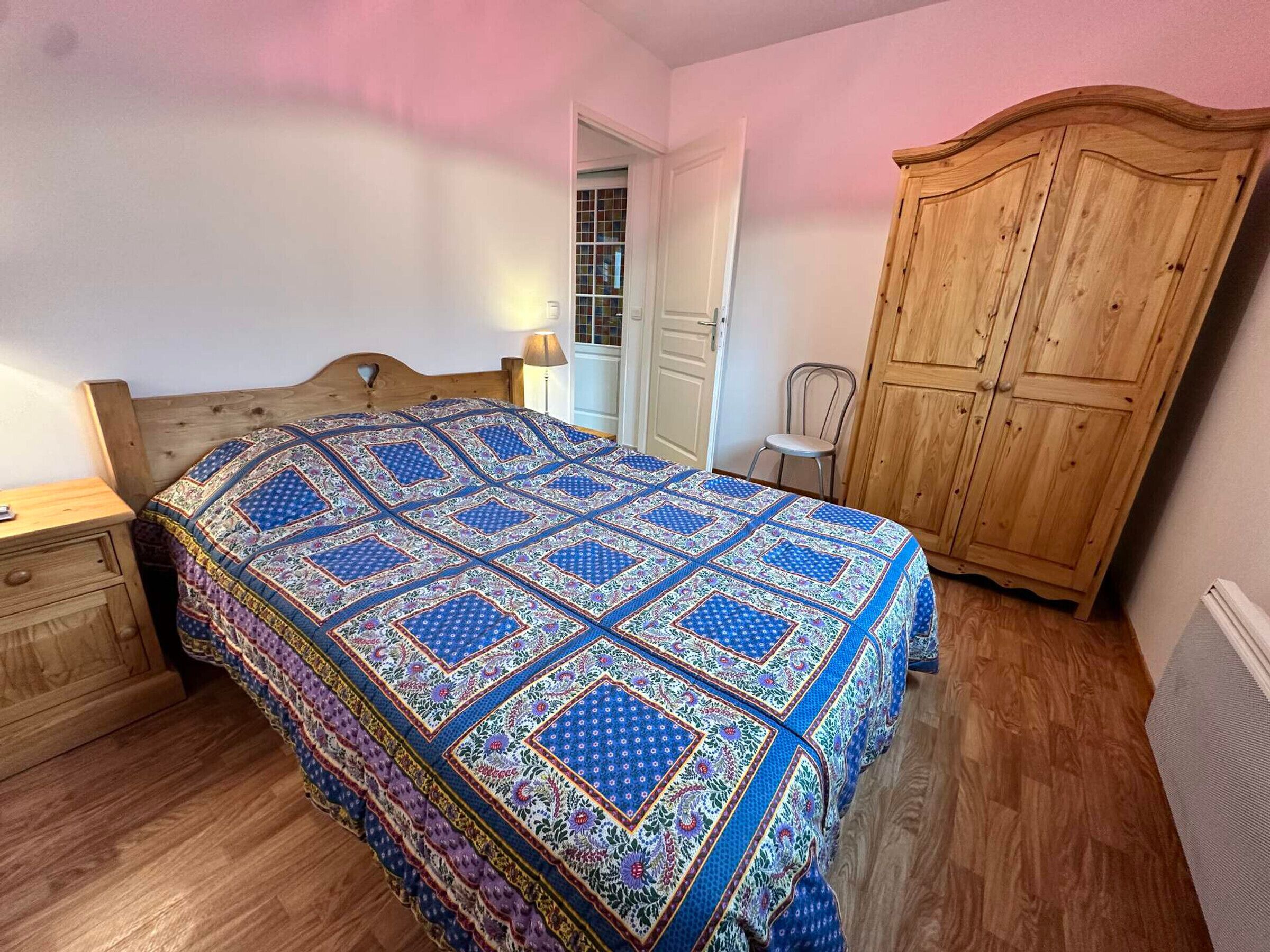 Un dormitorio con una cama de madera, un armario de madera y una mesita de noche.