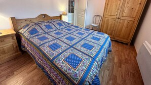 Een slaapkamer met een houten bed, een kledingkast van hout en een nachtkastje.