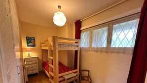 A bunk bed room with a wooden floor, a desk with a lamp, a chair, and a window with curtains. - Cozy apartment in Villard-de-Lans, 4 people, 52 m² (Villard-de-Lans)