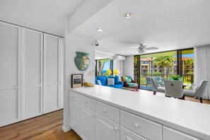 Una cocina moderna con armarios blancos, una isla grande y vistas a un balcón con mobiliario exterior.