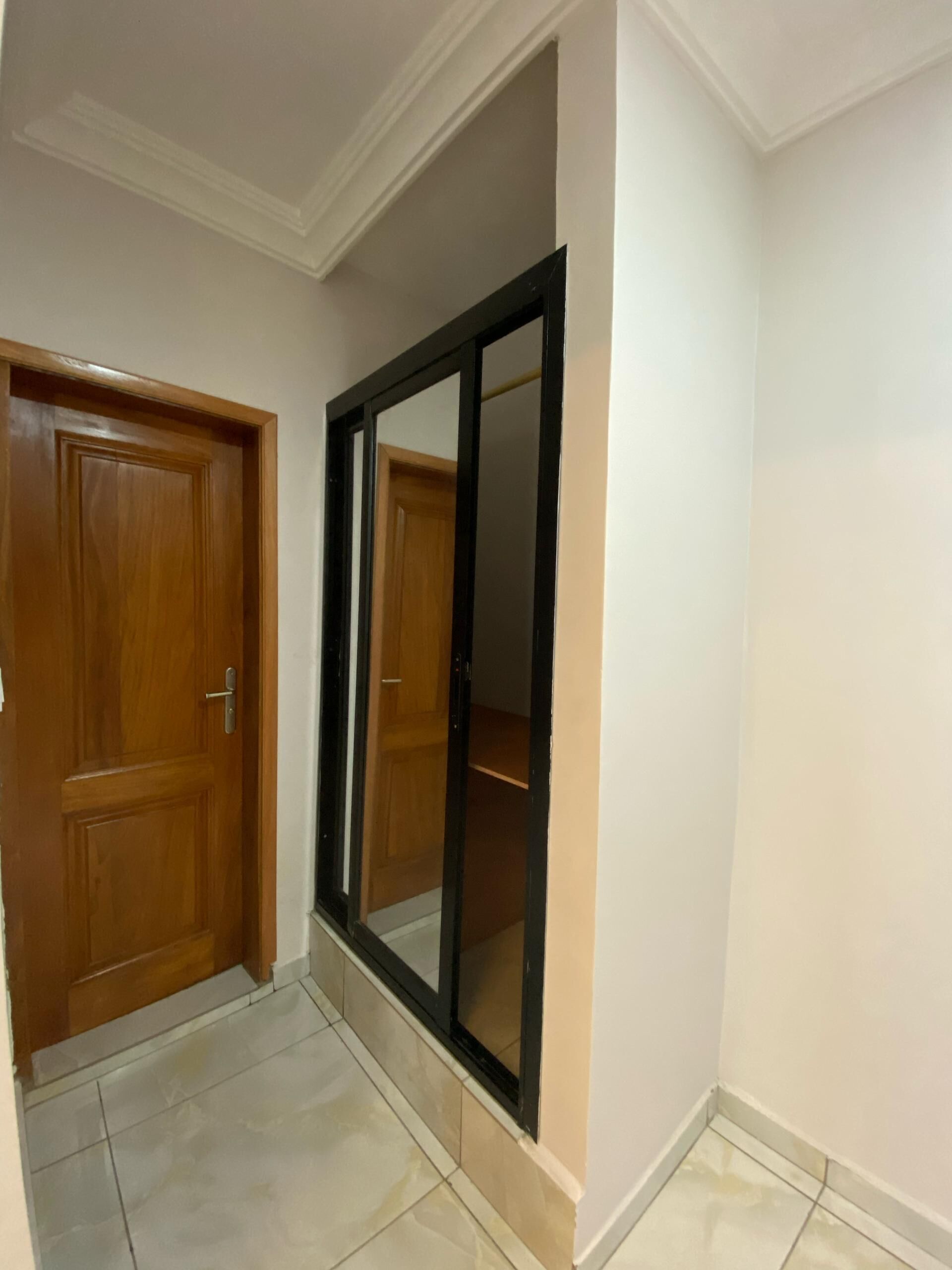 A hallway with a wooden door and a mirrored closet door.