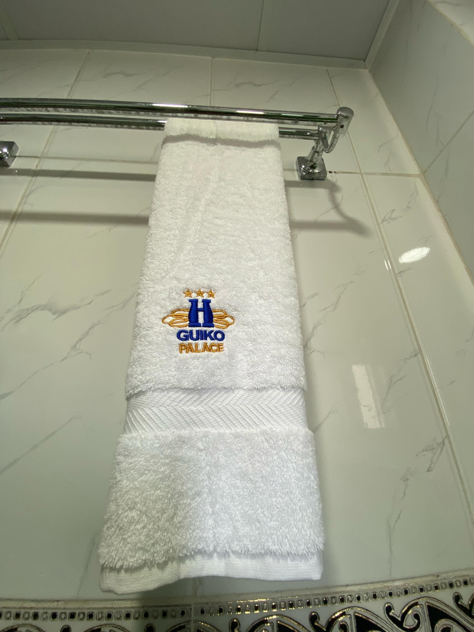 A white towel with a logo and text on a bathroom wall.