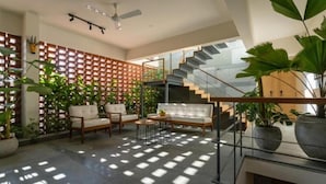 Ein modernes Wohnzimmer mit Treppe, Sofa, Couchtisch und Topfpflanzen.