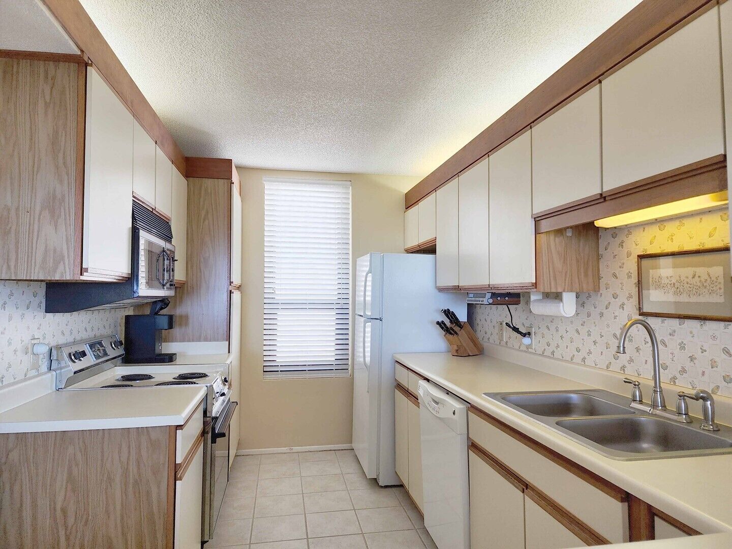 A compact kitchen with a stove, microwave, refrigerator, and sink.