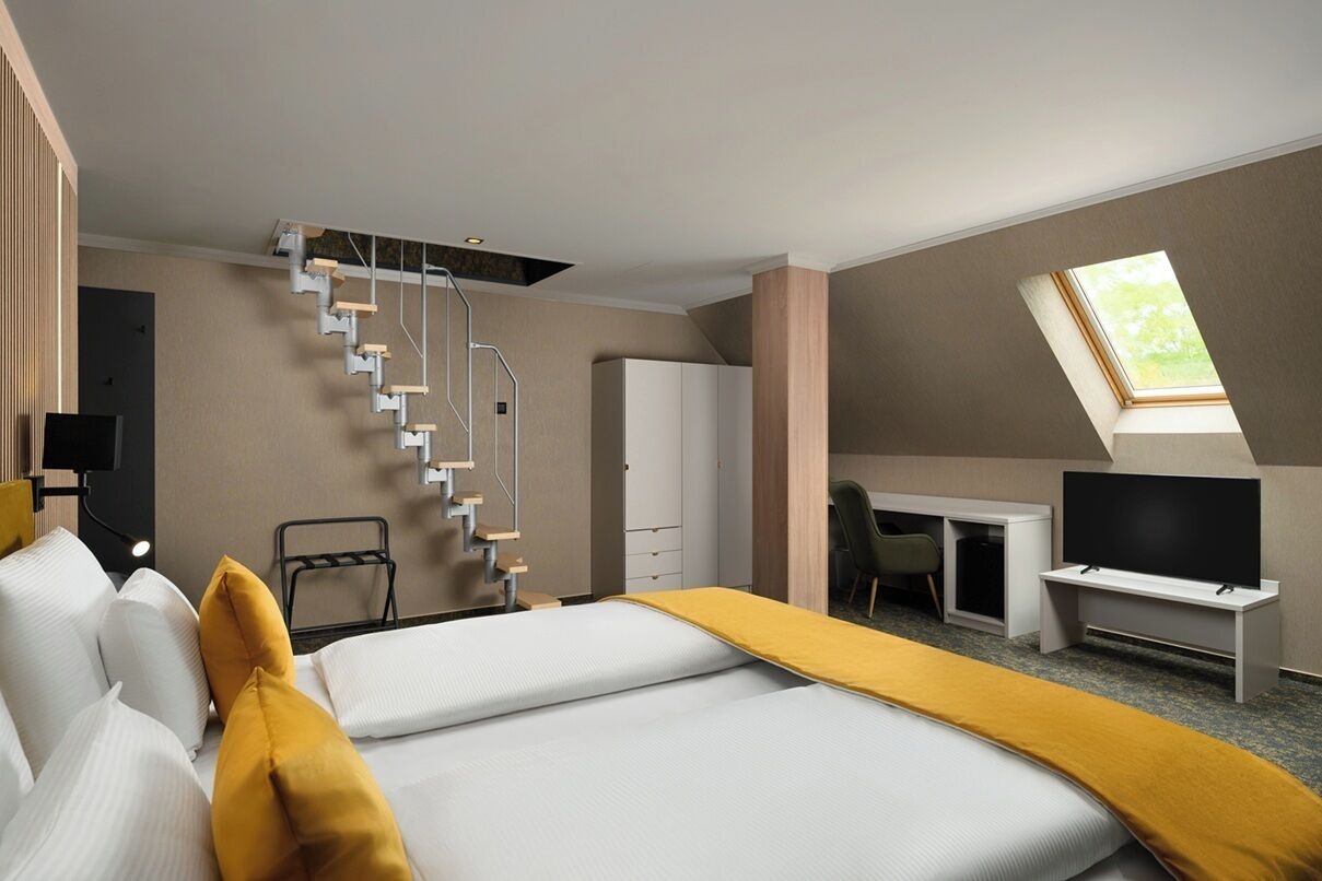 Ein Hotelzimmer mit Bett, Schreibtisch, Stuhl, Fernseher und einer Treppe.