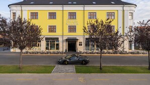 A yellow building with the sign "HOTEL ALLORA" and a black car parked in front.