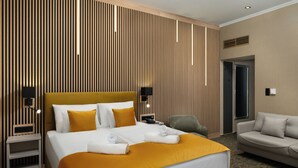 A hotel room with a large bed, a sofa, a desk, and a wall with vertical wooden slats.