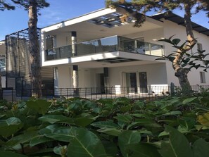 A modern two-story building with a glass balcony, large windows, and a minimalist design.