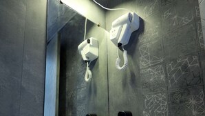 A bathroom with a white sink, a hairdryer, a mirror, and a telephone. - 1 BHK Suite ( Gagal Home) (Mumbai)