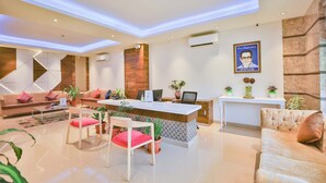A modern reception area with a desk, chairs, sofas, and potted plants.