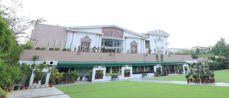 A hotel with a central courtyard, a covered outdoor seating area, and a classical facade with decorative elements.