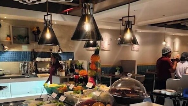 A buffet area with various food items and a person serving.