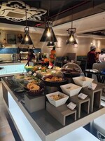 Uma área de buffet com diversos alimentos e um atendente.