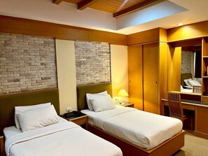 A hotel room with two single beds, a wooden wardrobe, a desk, and a mirror. - The Rich Hotel Rama 5 (Nonthaburi)