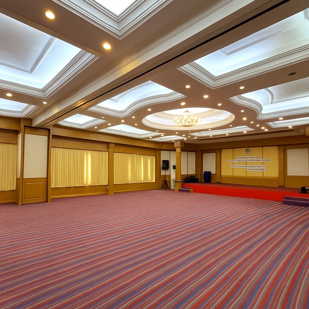 Un amplio salón de conferencias con techo alto, iluminación empotrada y un candelabro central.