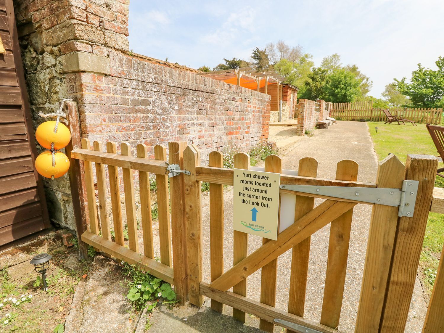 A wooden gate with a sign indicating the location of the Yurt shower rooms.