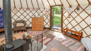 A cozy interior of a tent with a fireplace, a wooden dresser, a sofa, and a bench. - Stardust (Ventnor)