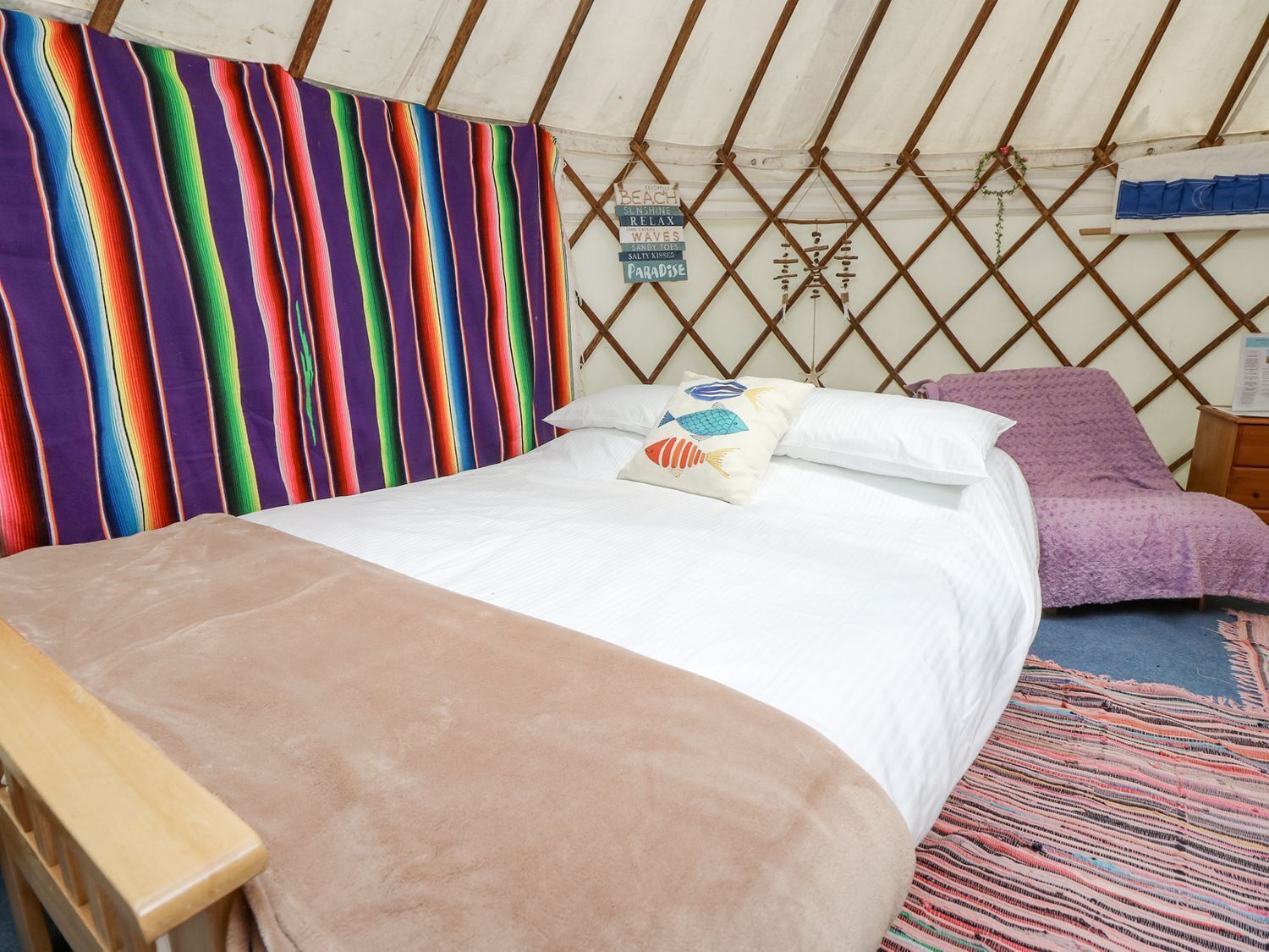 A cozy interior of a yurt with a bed, pillows, and a wooden bench.