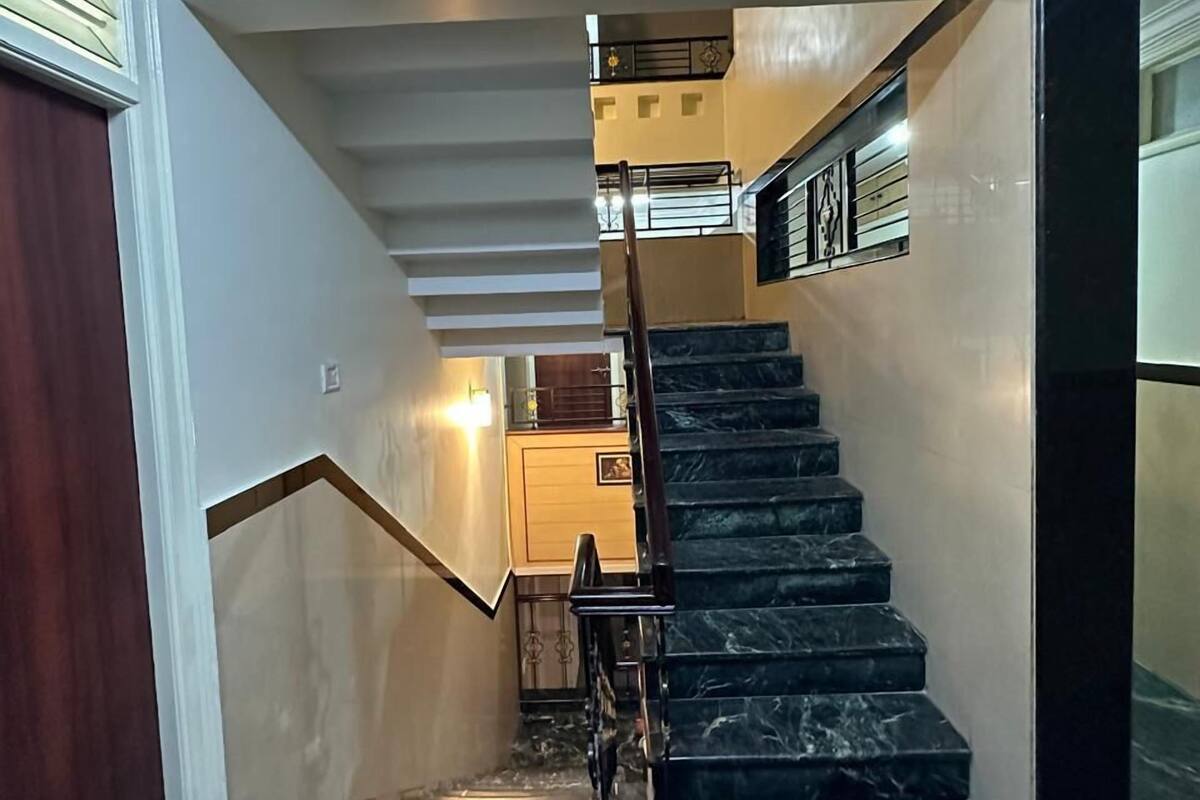 A staircase with dark marble steps and a wooden handrail, leading to a landing with a light fixture.