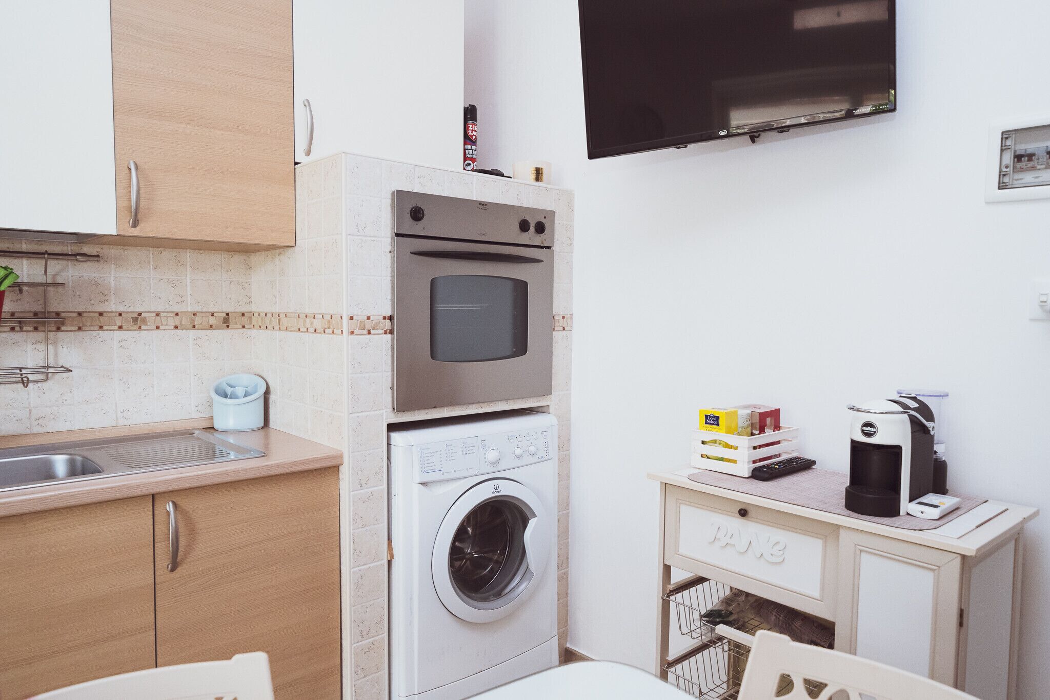 A compact kitchen with a built-in oven, microwave, and washing machine.