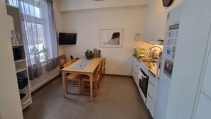A compact kitchen with a dining table, chairs, a refrigerator, and a sink.