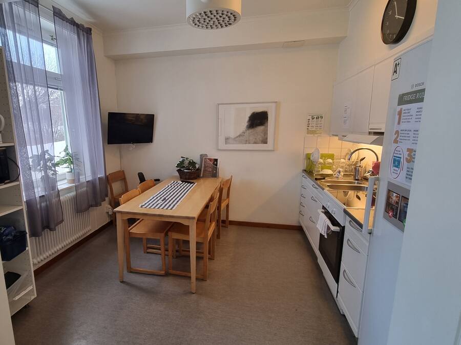 A compact kitchen with a dining table, chairs, a refrigerator, and a sink.