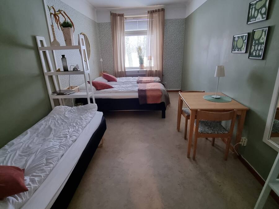 A dormitory room with bunk beds, a desk, and a mirror.