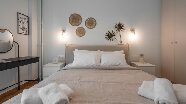 Un dormitorio ordenado con cama, mesitas de noche, escritorio y silla.