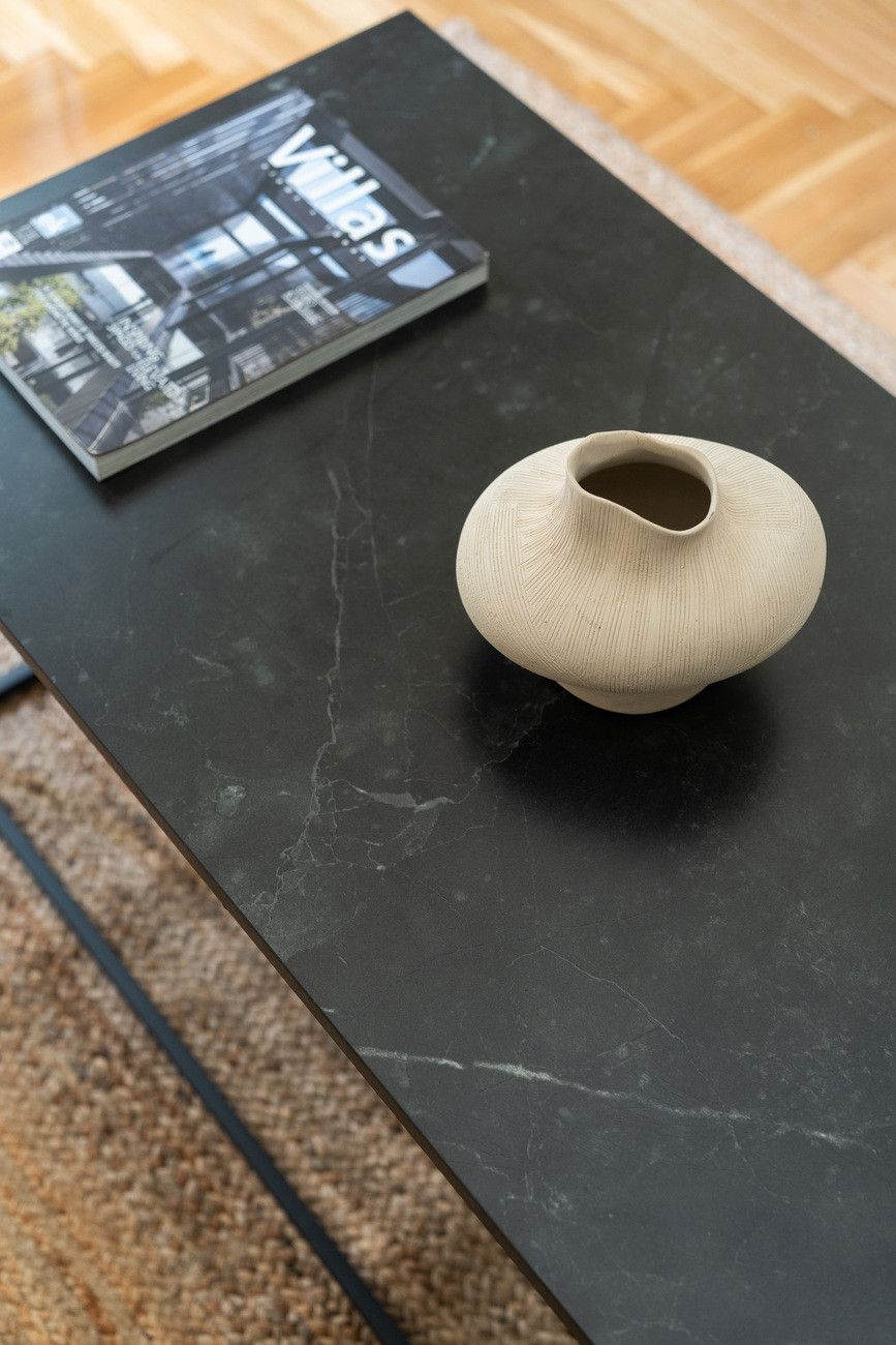 Un florero sobre una mesa negra con una revista titulada “Villas” a su lado.
