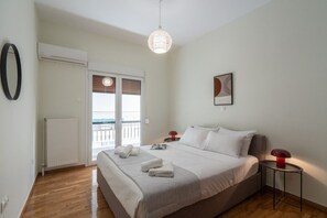A hotel room with a bed, a bedside table, a lamp, a radiator, a window with blinds, and a view of the outside. - LIV - Relaxing Pagrati Retreat in Athens (Athens)