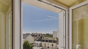 A view through a window of a building with multiple floors, featuring a clear sky and distant buildings. - The port and beaches nearby - 2 adults 2 children (Concarneau)