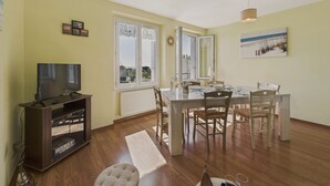 A living room with a TV, dining table, chairs, and a window with a view. - The port and beaches nearby - 2 adults 2 children (Concarneau)