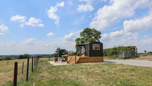 Une petite cabane à un seul étage, dotée d’une terrasse en bois et d’un escalier menant à l’entrée.