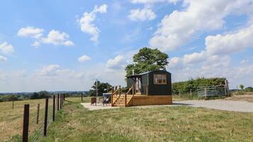 A small, single-story cabin with a wooden deck and a staircase leading to the entrance.