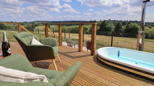 Une terrasse en bois avec un canapé vert et un jacuzzi.