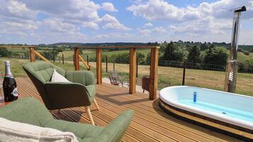 A wooden deck with a green sofa and a hot tub.
