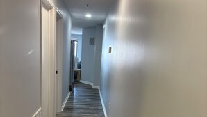 A hallway with wooden flooring, white walls, and a door at the end. - Book Fast! 2BR/2BA Ocean Block—Steps to Beach, Walk to Top Restaurants &! (Ocean City)