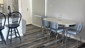 A modern kitchen with a dining area, featuring a round table with chairs, a built-in oven, and a backsplash with a stone-like texture. - Book Fast! 2BR/2BA Ocean Block—Steps to Beach, Walk to Top Restaurants &! (Ocean City)