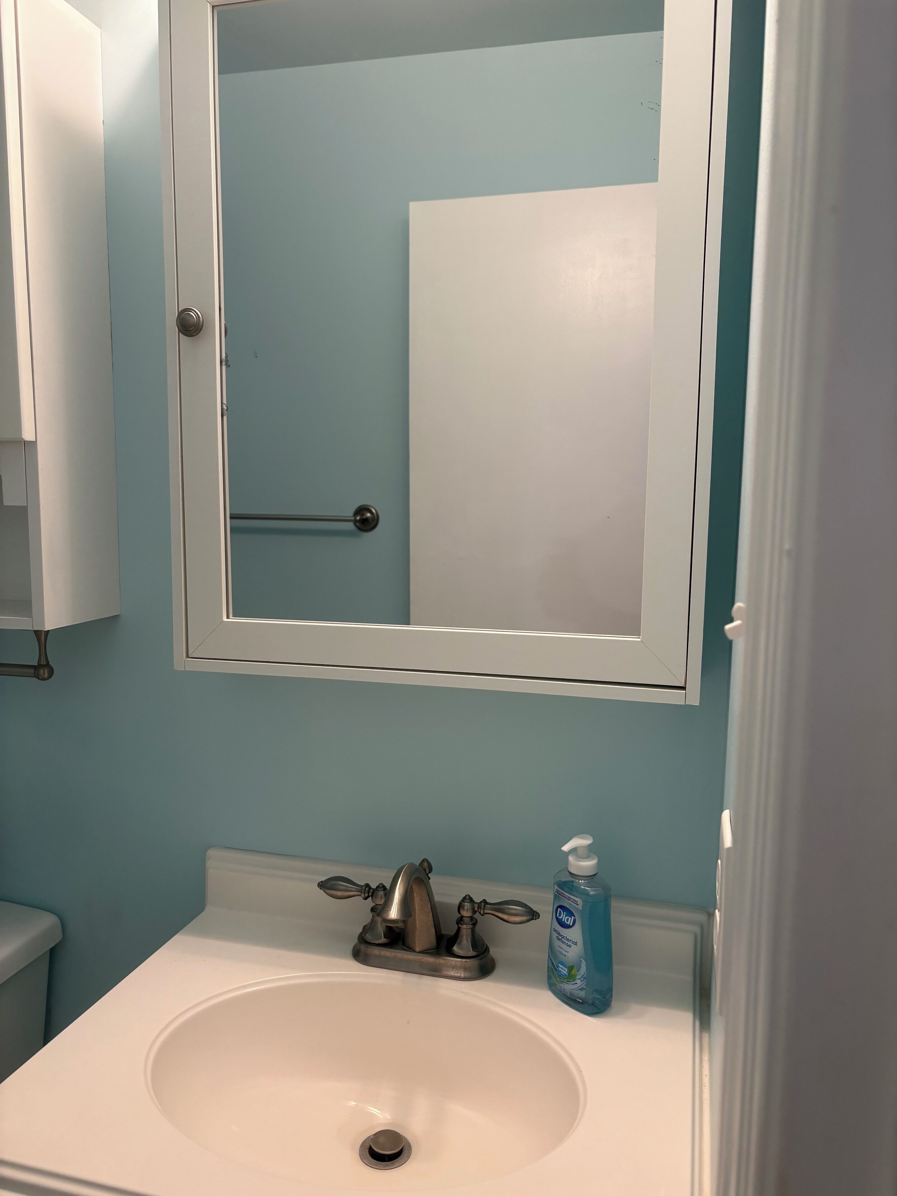 Ein Badezimmer mit einem weißen Waschbecken, einem Spiegel und einer blauen Wand.