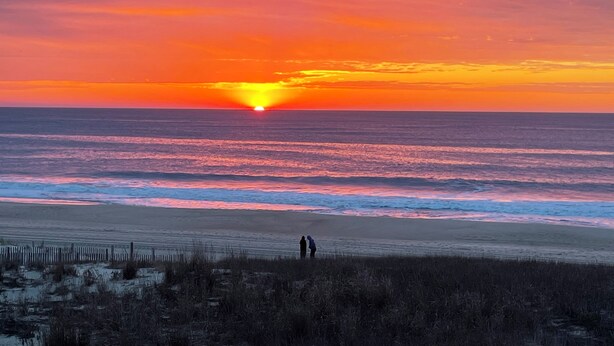 A beach with a sunset, ocean waves, and a person walking. - Book Fast! 2BR/2BA Ocean Block—Steps to Beach, Walk to Top Restaurants &! (Ocean City)