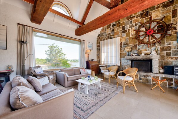 Relax in this inviting living room with a high ceiling, comfortable sofa, and fireplace.