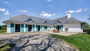 Une maison à deux étages avec un patio couvert, une allée en gravier et une pelouse.