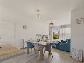 A modern living room with a dining area, a sofa, and a table with chairs.