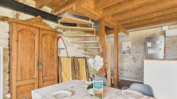 Un coin repas avec une table dressée pour deux personnes, un buffet en bois, une planche de surf et un réfrigérateur.