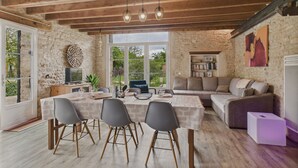 Ein rustikales Interieur mit Esstisch, Stühlen, einer Couch und einem Bücherregal.